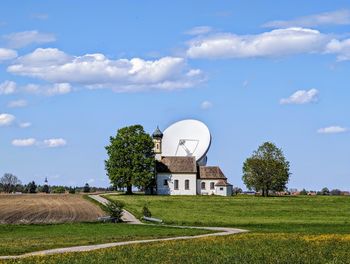 Scenic view of field against sky with church and satellite antenna
