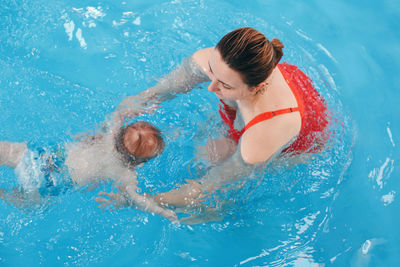 High angle view of woman holding baby boy in swimming pool
