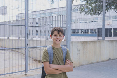 Portrait of smiling boy standing by fence