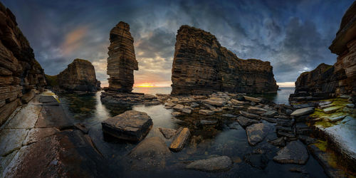 Panoramic shot of rock formations by sea against sky