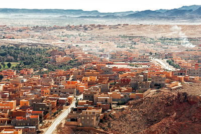 Panorama of berber city of tinghir in sahara desert against red canyon and mountains, morocco