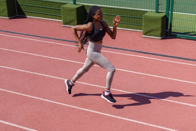 African woman athlete running on racetrack. sportive black female training jog on stadium sprinting