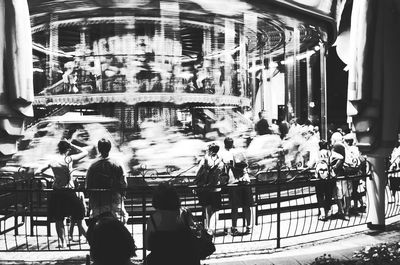 Rear view of people at amusement park in city at night