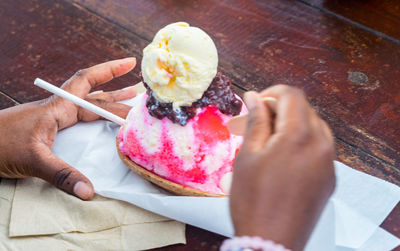 Hand holding ice cream cone on table