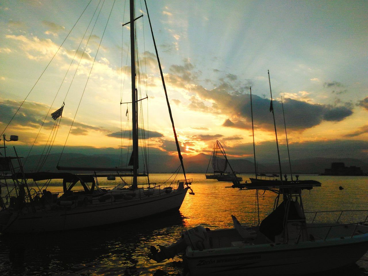 nautical vessel, transportation, boat, sunset, mode of transport, water, moored, sky, mast, cloud - sky, sea, sailboat, orange color, beauty in nature, cloudy, scenics, travel, cloud, reflection, nature