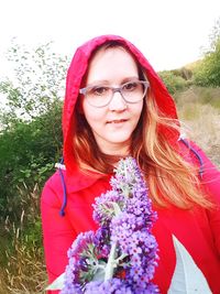 Portrait of smiling woman standing by pink flowering plants