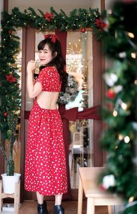 Portrait of young woman standing against christmas tree