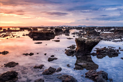 Rocks in calm sea against the sky