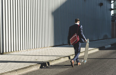 Young businessman walking with skateboard on the street