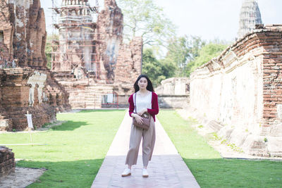 Full length portrait of smiling young woman standing in temple