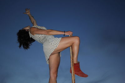 Low angle view of woman against blue sky