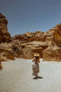 Rear view of woman standing on mountain against clear sky