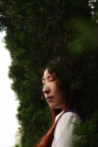 Young woman with eyes closed against plants