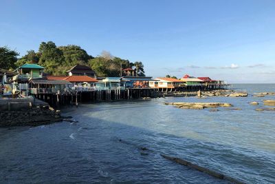 Houses by sea against sky