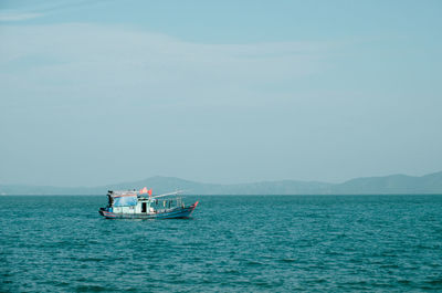 People in boat sailing on sea against sky