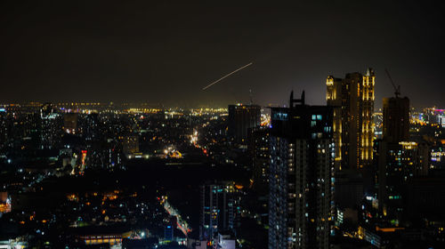 Illuminated buildings in city against sky at night