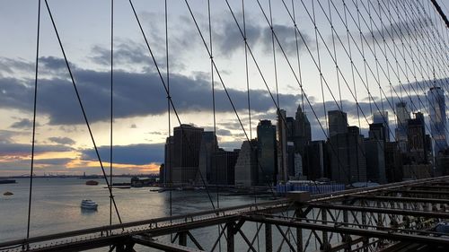 View of suspension bridge and buildings against sky during sunset