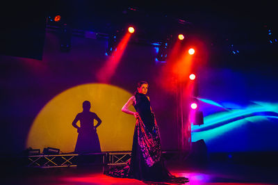 Man standing by illuminated lighting equipment at night