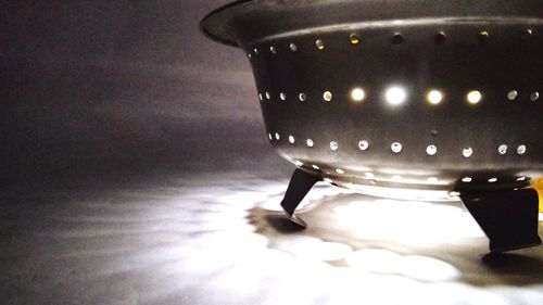 Close-up of illuminated lighting equipment on table against wall