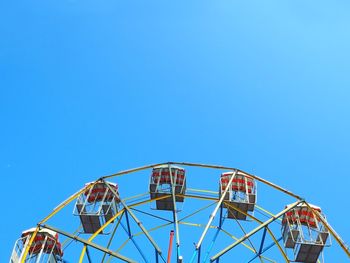 Low angle view of ferris wheel against blue sky