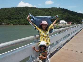Portrait of mother and daughter standing by railing on footbridge
