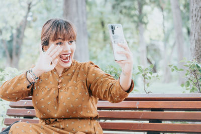 Young woman using mobile phone while sitting on bench