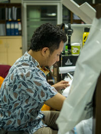 Rear view of man looking at camera while standing on table