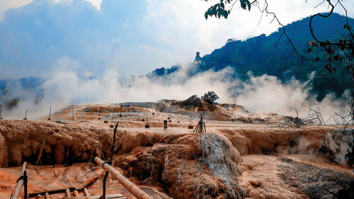 Panoramic view of smoke emitting from land against sky