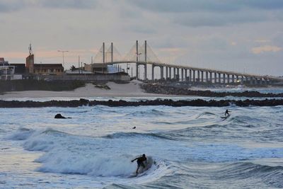 People surfing in sea against sky