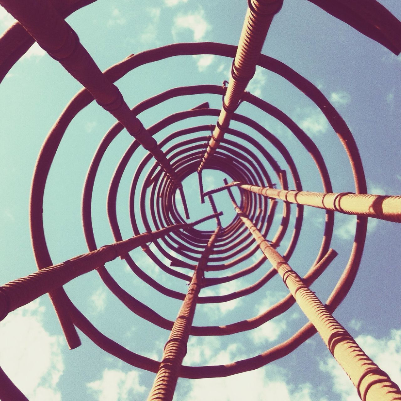 low angle view, metal, sky, amusement park, metallic, pattern, amusement park ride, ferris wheel, built structure, arts culture and entertainment, day, no people, cloud - sky, outdoors, spiral, directly below, protection, tall - high, architecture, circle