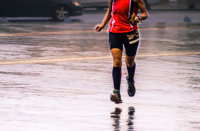 Low section of man running on wet beach