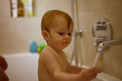 Cute little baby girl having shower in bathtub