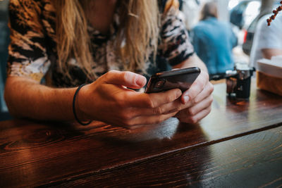 Midsection of woman using mobile phone on table