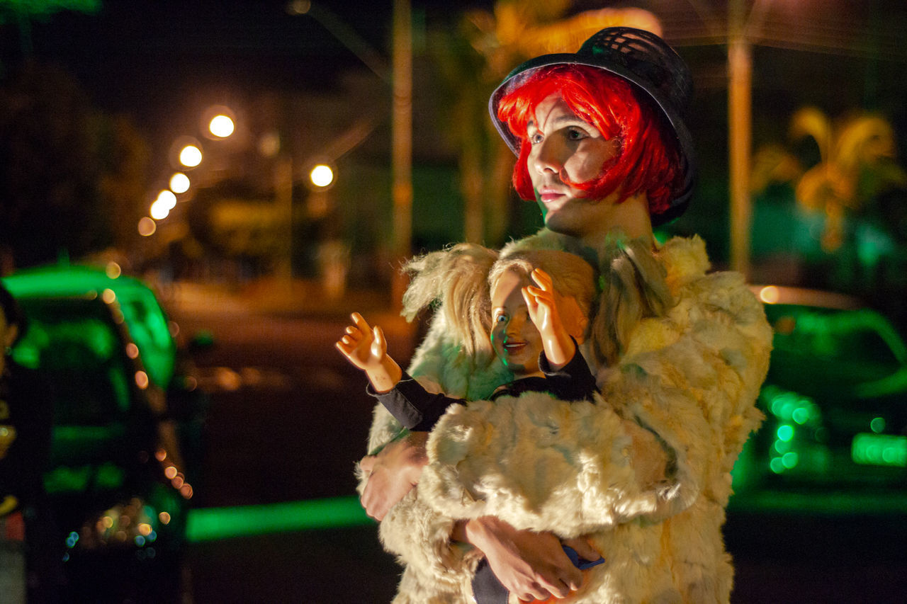 night, focus on foreground, representation, human representation, illuminated, toy, one person, waist up, outdoors, costume, motor vehicle, car, clothing, transportation, mode of transportation, female likeness, three quarter length