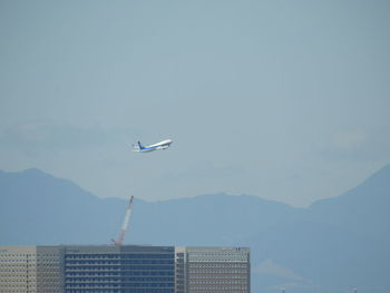 Airplane flying over mountain against sky
