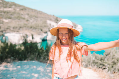 Portrait of young woman wearing hat standing at beach