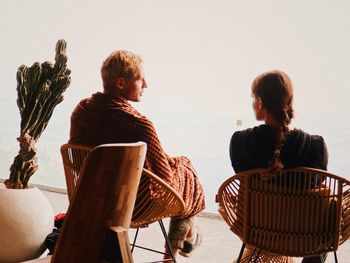 Rear view of people sitting in sea against clear sky