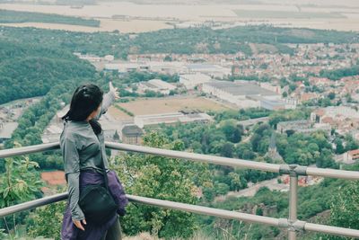 Woman with arm outstretched standing by railing