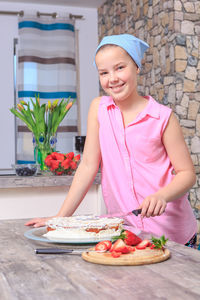 Portrait of smiling teenage girl cutting cake
