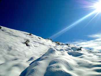 Scenic view of snow covered mountain against blue sky