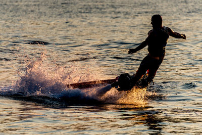 Man flyboarding in sea during sunset