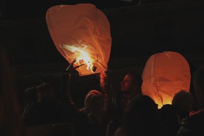 People holding burning fire at night