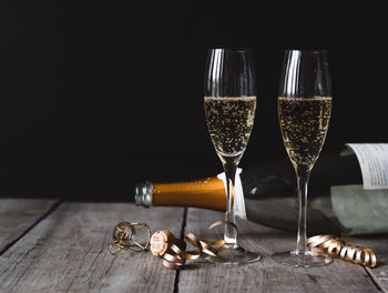 Two glasses of champagne and empty bottle with black background.