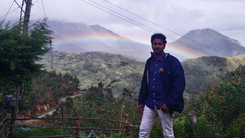 Portrait of young man standing on mountain against sky