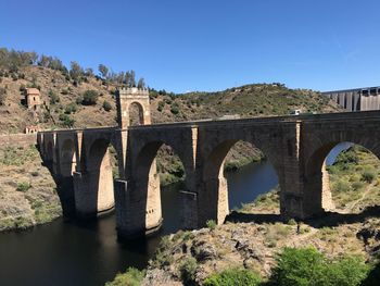 Arch bridge over river against blue sky