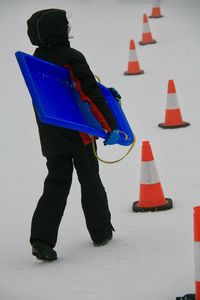 Rear view of man with umbrella standing in snow