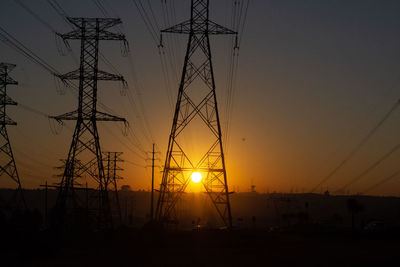 Silhouette electricity pylon against sky during sunset