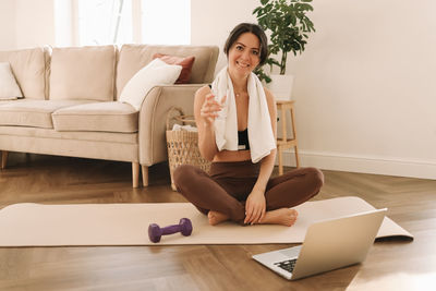 Fitness girl looks at her laptop while doing sports training and physical activity at home