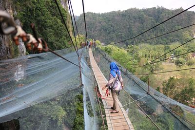 Panoramic view of footbridge amidst trees and mountains