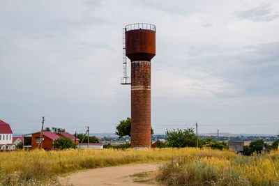 Lighthouse on field against sky